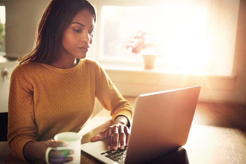 3 Top Canadian Stocks to Buy With $500 This September Woman checking her computer and holding coffee cup