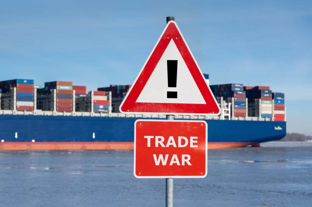 Is Bombardier Stock a Buy or Sell in the Escalating Trade War? Warning sign with the text "Trade war" in front of container ship